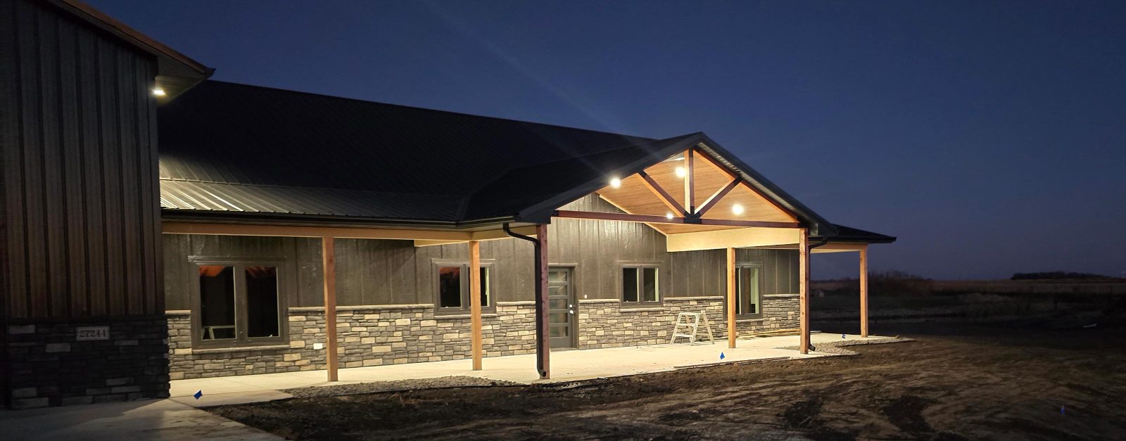 Custom home exterior at dusk with timber porch and stone accents, built by Hahn Custom Homes