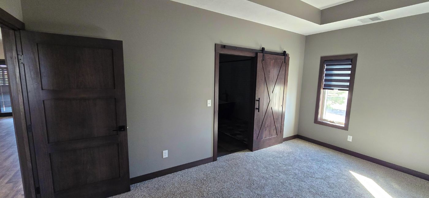 Living room with shiplap fireplace wall, vaulted wood ceiling and patio doors, custom home South Dakota